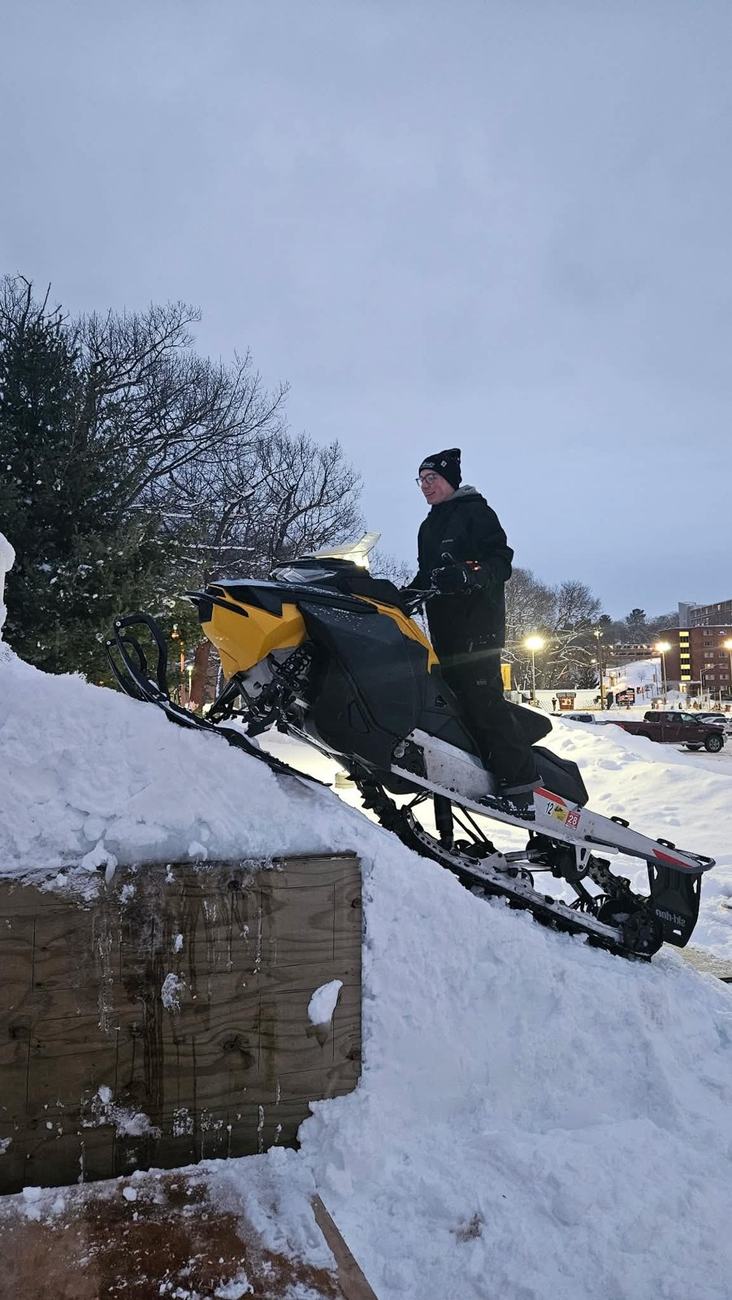 Riding a snowmobile off the Winter Carnival snow ramp